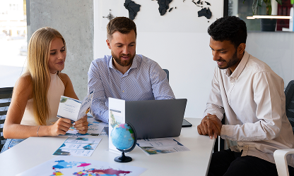 A diverse group of three colleagues reviewing business brochures and global strategies around a laptop at WorthLift.