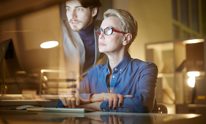 Two professionals analyzing digital strategy and data on a computer screen in a modern office setup.